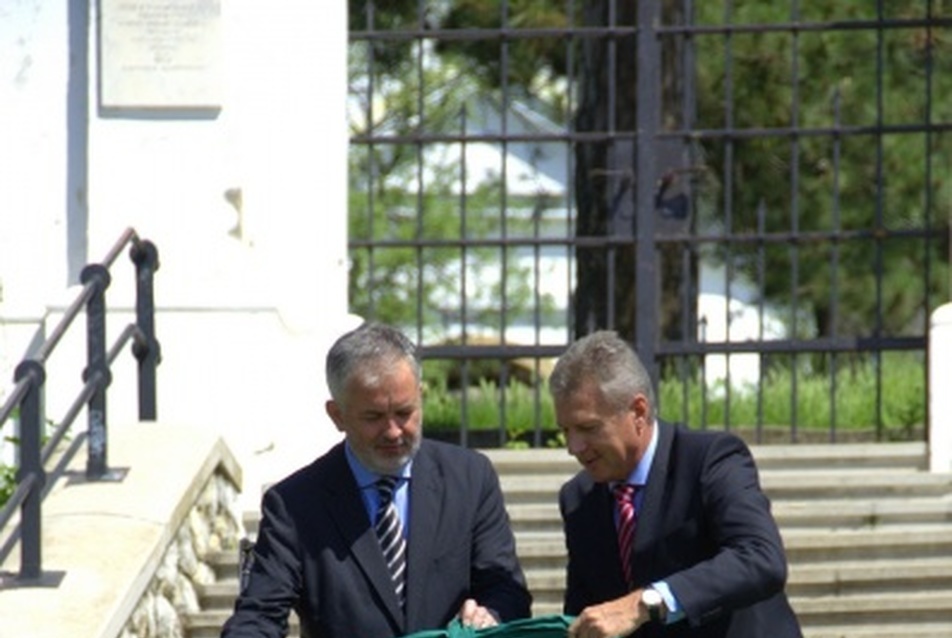 Szarkándi János, a DDC elnök-vezérigazgatója és dr. Páva Zsolt Pécs polgármestere, amint kibontják a Kálvária-domb lépcsőjénél az ajándékot jelképező zöld masnit.