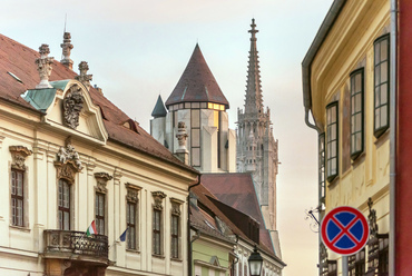 A Mátyás-templom, és a Szent Miklós Torony a Táncsics Mihály utcából. Balra a 7. házszám alatti főnemesi palota, ma MTA Zenetudományi Intézet.