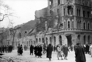 Az Üllői út és a Nagy Templom utca sarka 1956 után. A sarkon álló historizáló házat helyreállították, a távolabbi, alacsony épületek helyére került Schall József lakóháza. Fotó: Fortepan / Gödér Hajnal