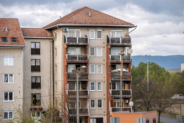 A szomszédos Ráckapu téren már meghatározó helyen is magastetős, a homlokzatán valódi  fa elemekkel tervezett ház jelzi a modernebb lakótelep szélét.